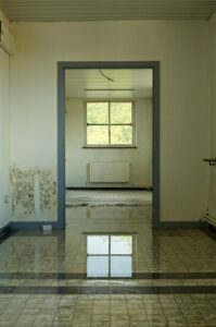 pexels-photo-18302377-18302377 An abandoned room with a flooded floor reflecting a window, highlighting decay and neglect.
