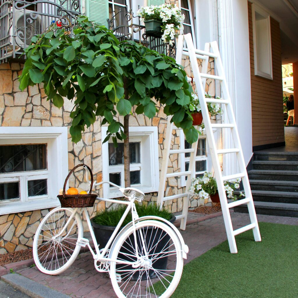 Hose for cleaning A stylish outdoor scene featuring a white bicycle, ladder, and lush greenery in a cozy setting.