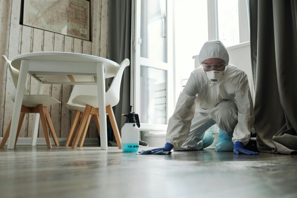 pexels-photo-4099087-4099087 Specialized cleaning person in protective suit disinfecting a floor indoors for hygiene and safety.