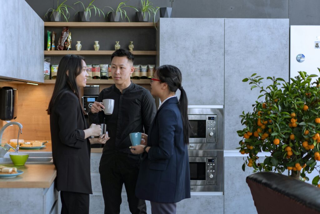 pexels-photo-8102047-8102047 Asian professionals enjoy a coffee break and conversation in a modern office kitchen.