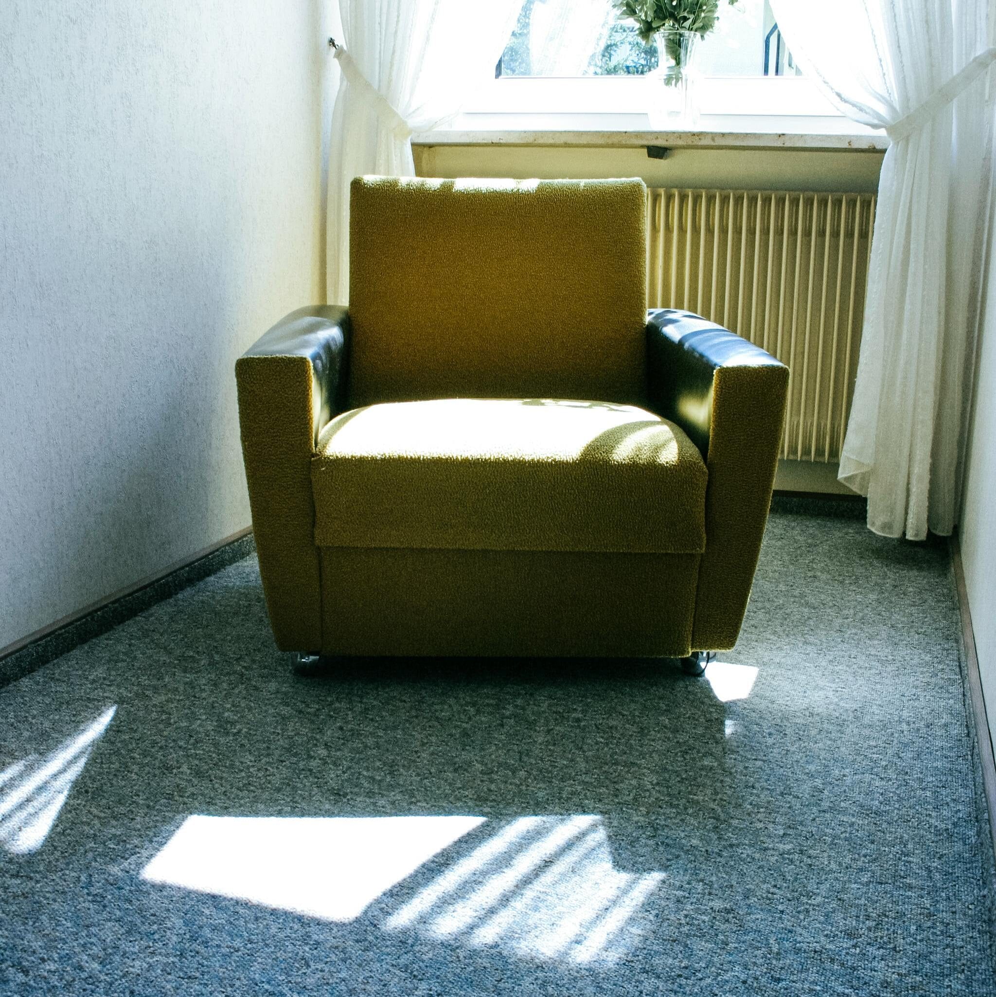 pexels-photo-105004-105004 Minimalist interior featuring a cozy armchair and flower vase by a sunlit window.
