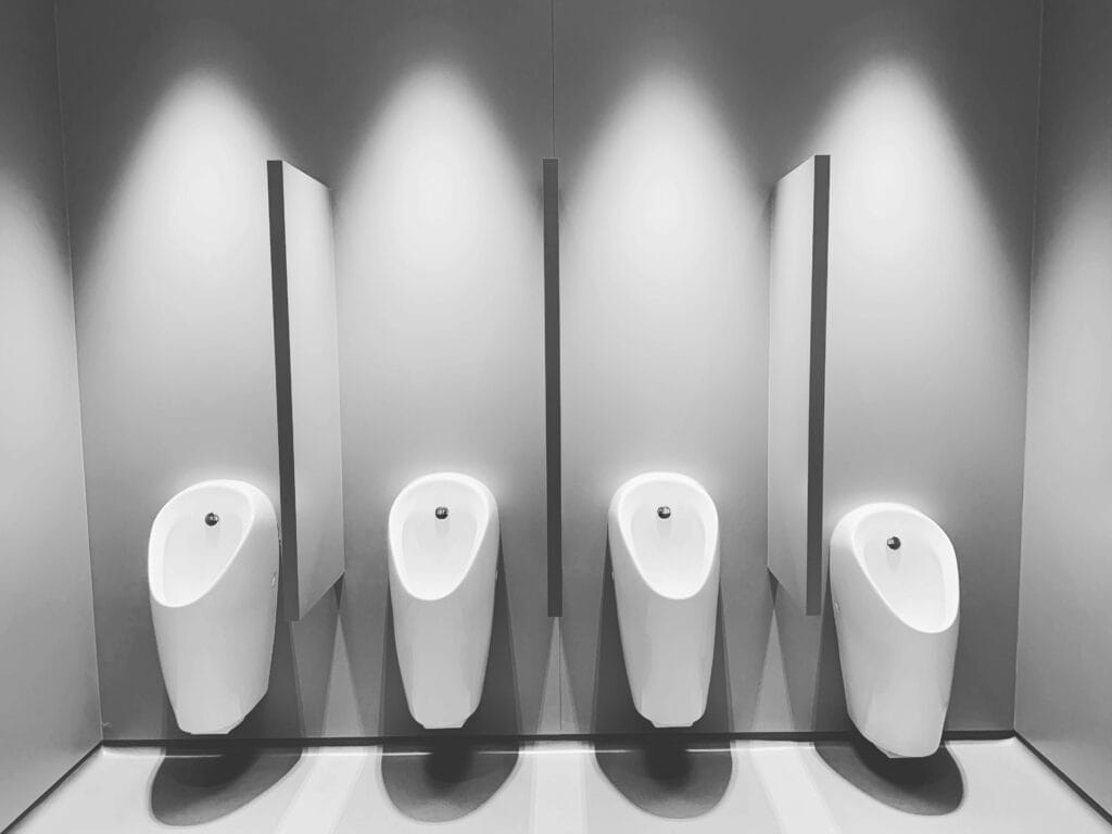 pexels-photo-13464442-13464442 A clean and modern restroom featuring four white urinals and partitions.
