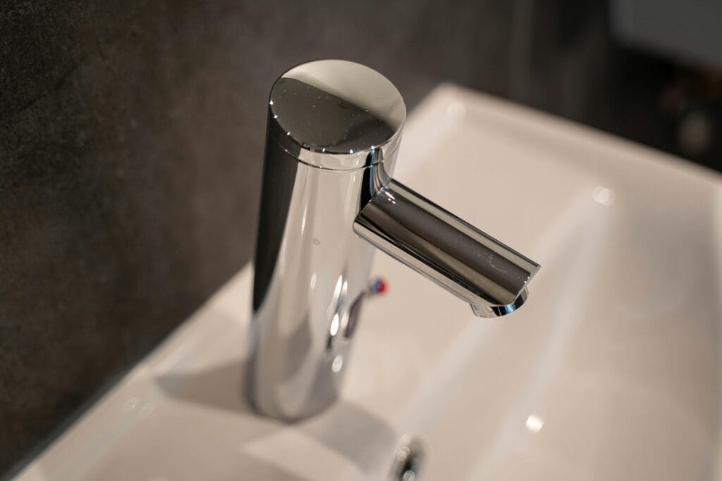pexels-photo-13963752-13963752 Close-up of a sleek stainless steel faucet on a ceramic sink, modern bathroom style.