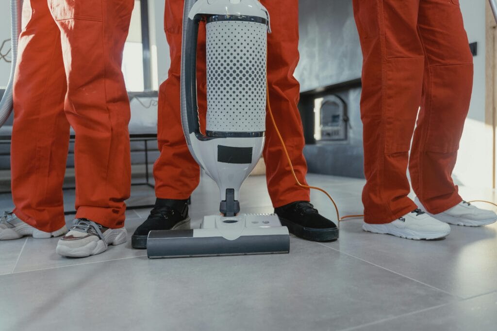 pexels-photo-6195122-6195122 Team of professional cleaners in red uniforms using a vacuum cleaner indoors.