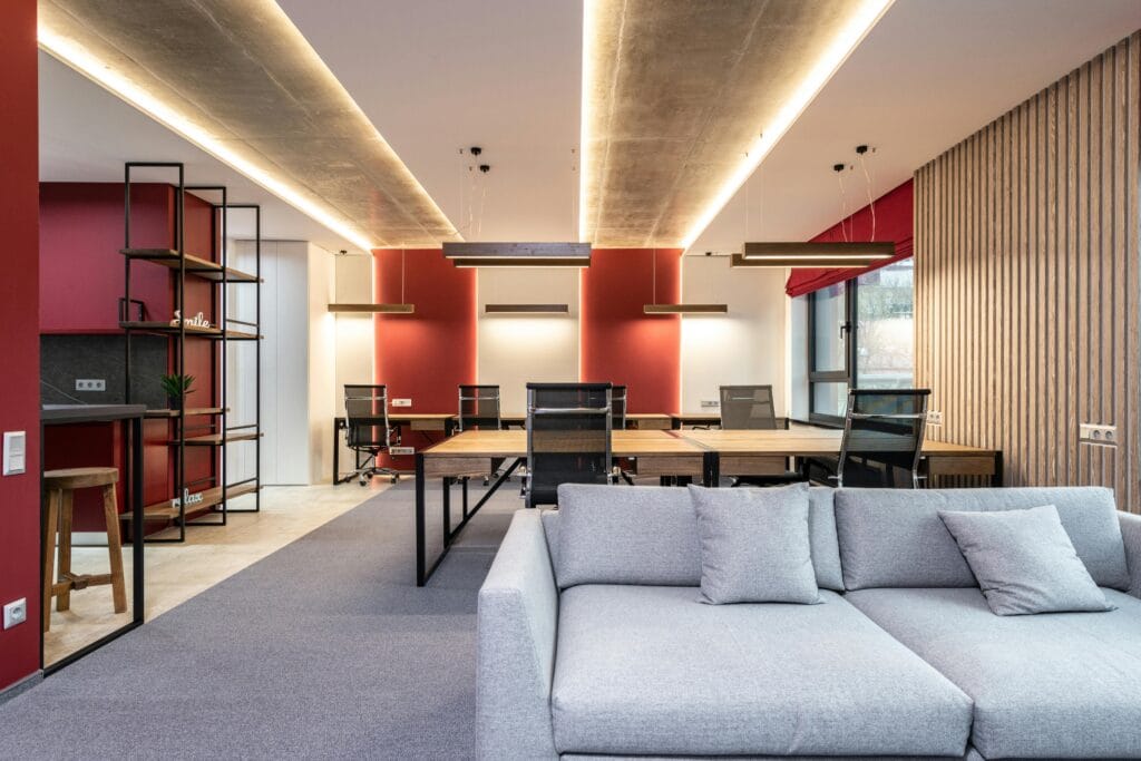 pexels-photo-6899397-6899397 Spacious modern office featuring red accent walls, stylish furniture, and ample natural light.