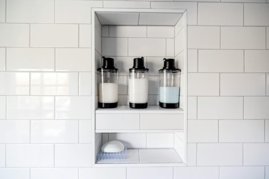 pexels-photo-7168085-7168085 Clean and minimalist bathroom design featuring soap dispensers and white tiles.