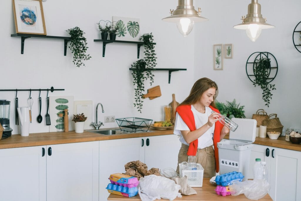 pexels-photo-7512869-7512869 Woman organizing recyclables in a contemporary kitchen setting, promoting eco-friendliness.