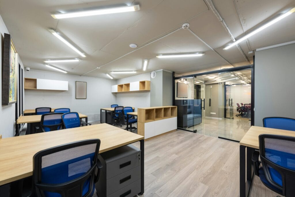 pexels-photo-7534175-7534175 Spacious modern office interior with wooden desks, blue chairs, and ample lighting.