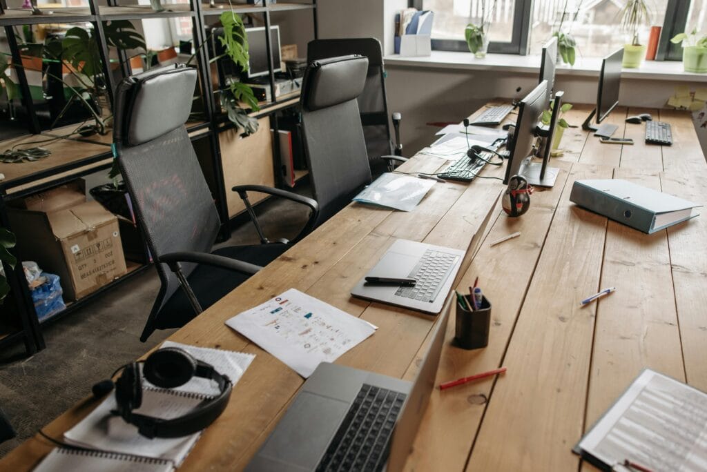 pexels-photo-7658310-7658310 Spacious co-working office with wooden desks, laptops, and modern chairs.