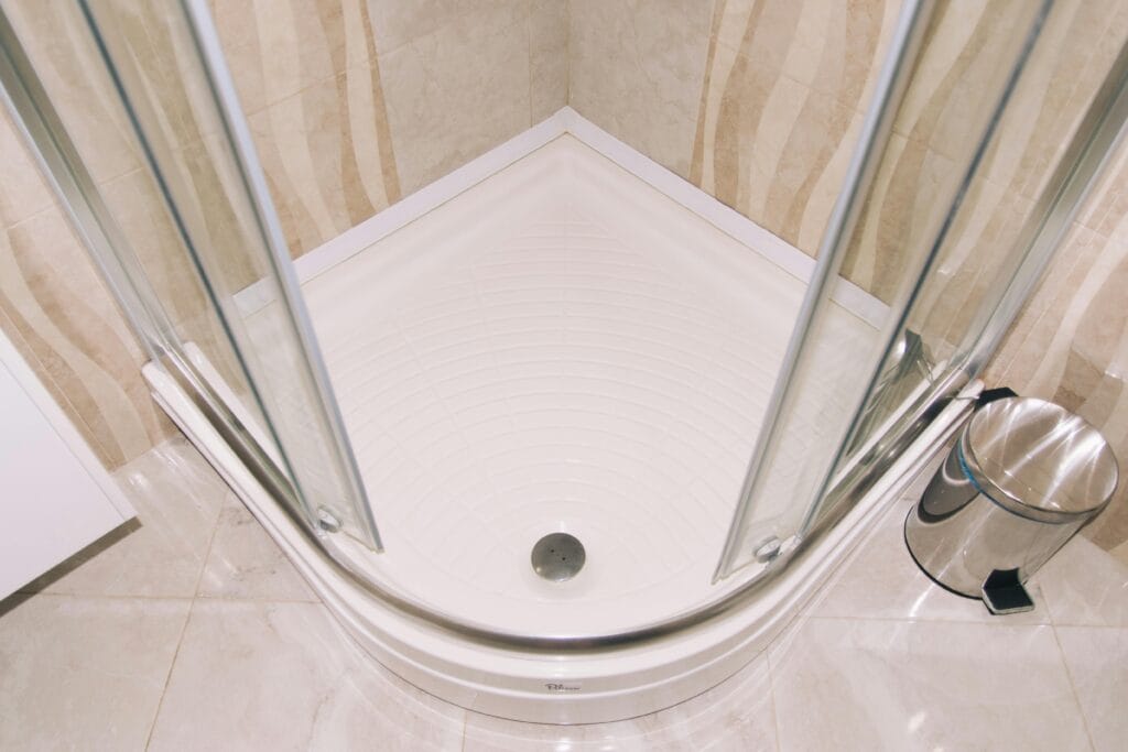 pexels-photo-9562379-9562379 A clean, modern corner shower enclosure with glass doors in a tiled bathroom setting.