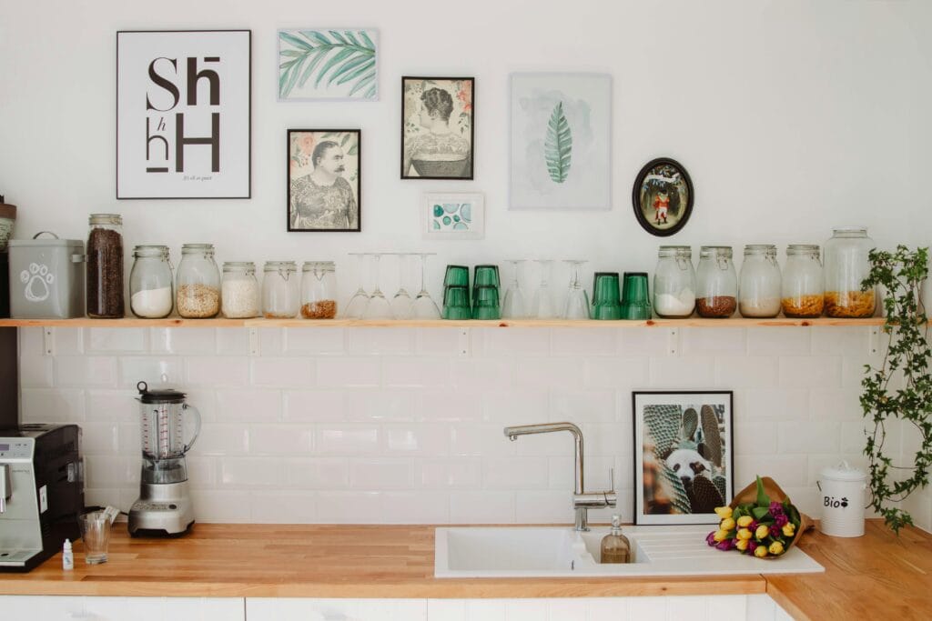 pexels-photo-9684571-9684571 Contemporary kitchen in Estonia featuring wooden shelves, decor elements, and glass jars above a sink.